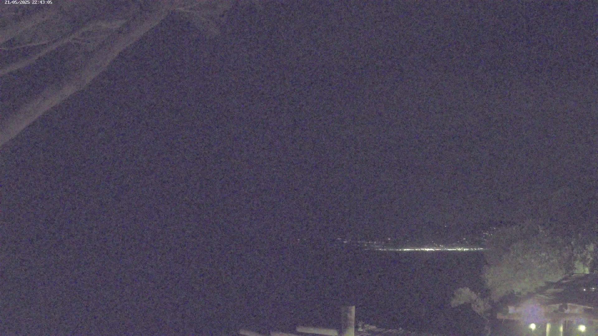 A nighttime view of a distant shoreline with faint lights, under a dark, clear sky.