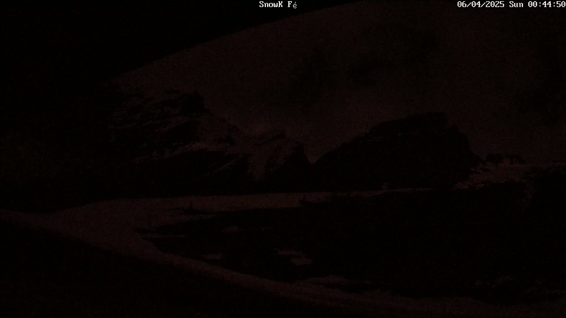 Dark, snow-covered mountains are visible under a nighttime sky.