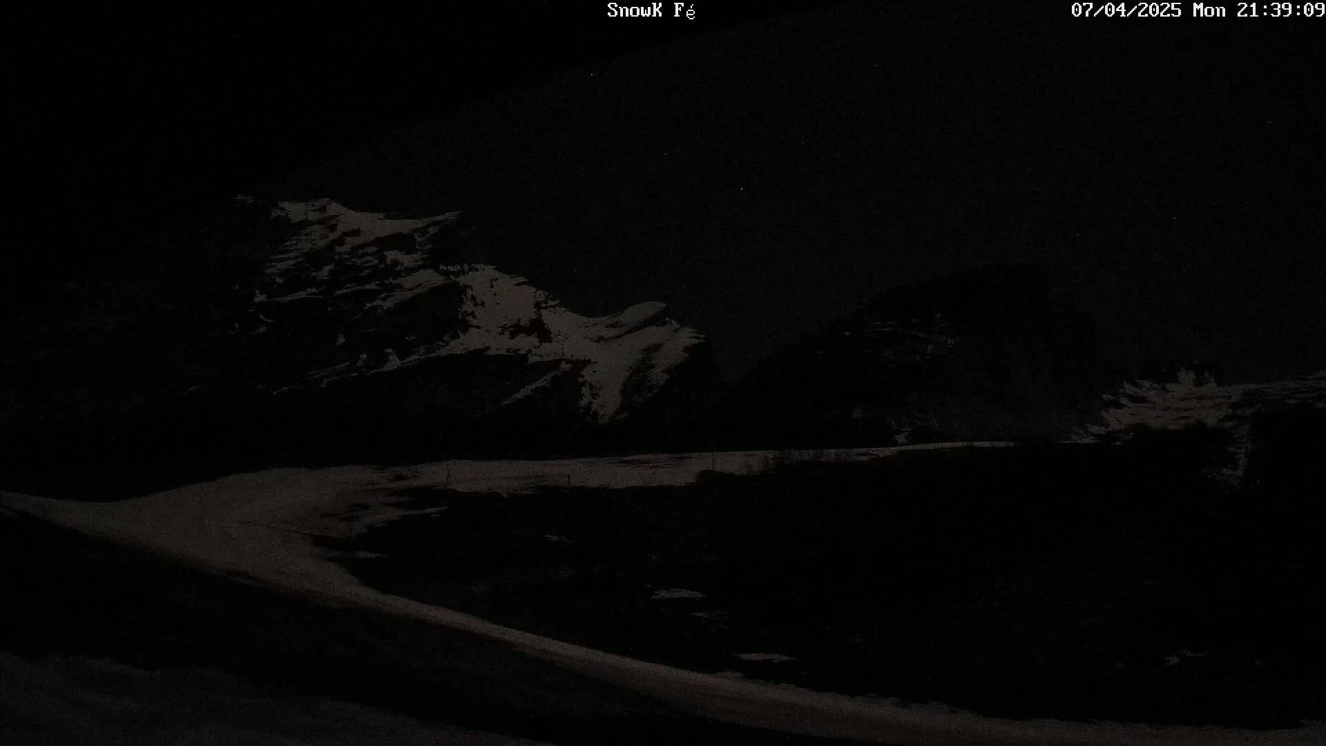 Snow-covered mountains are visible at night under a dark sky.