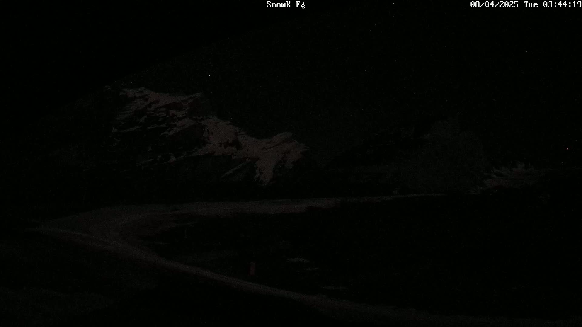 A dark, nighttime scene shows snow-covered mountains under a starry sky.