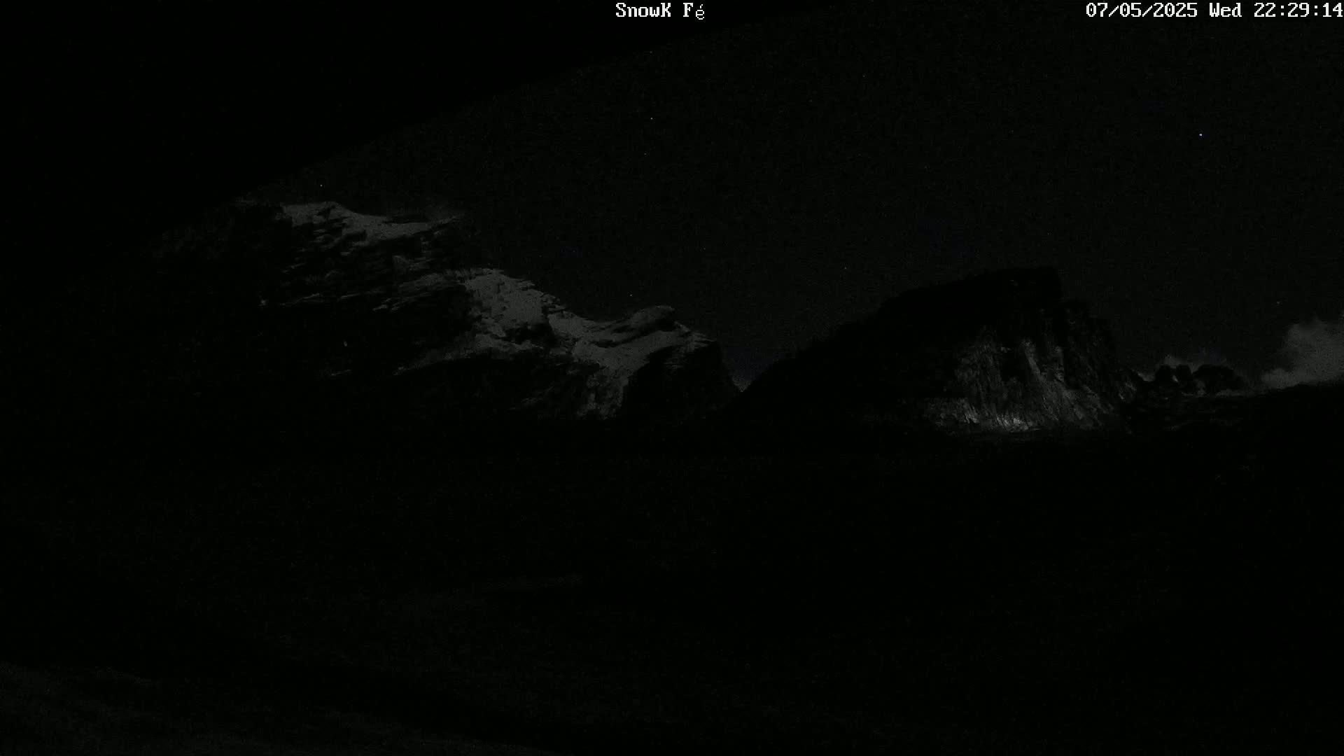 Snow-covered mountains are visible at night under a clear, starry sky.