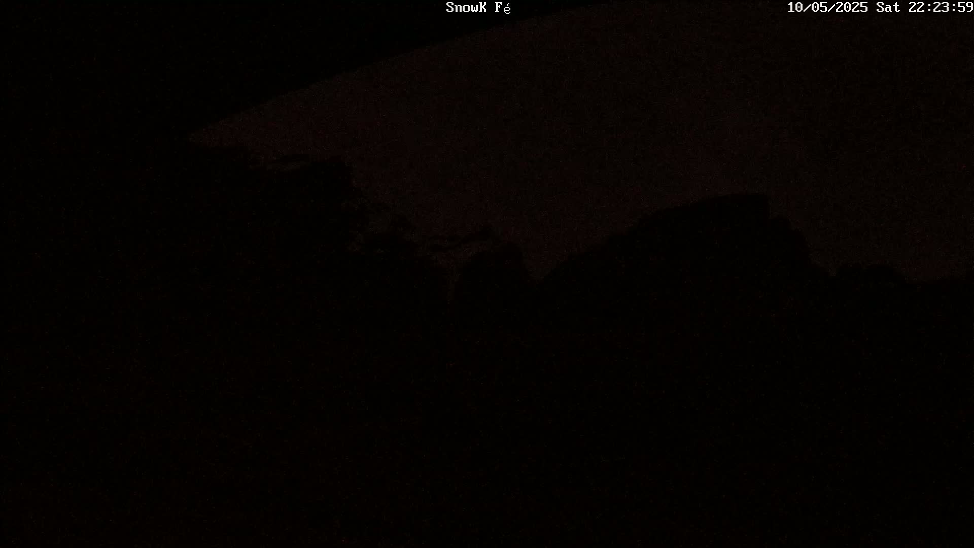 A dark, nighttime scene shows a silhouetted landscape under a mostly clear, dark sky.