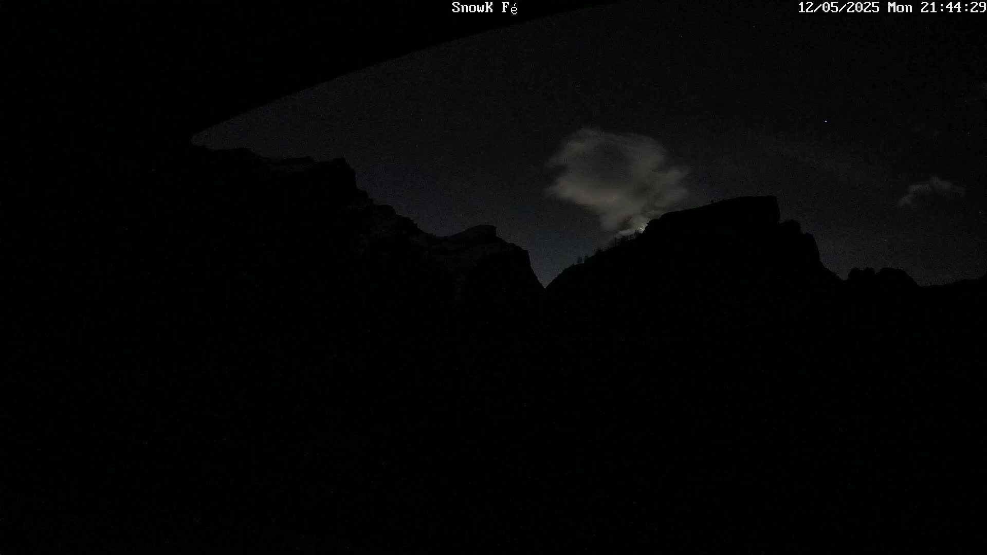 Silhouetted mountains are visible under a night sky with some clouds.