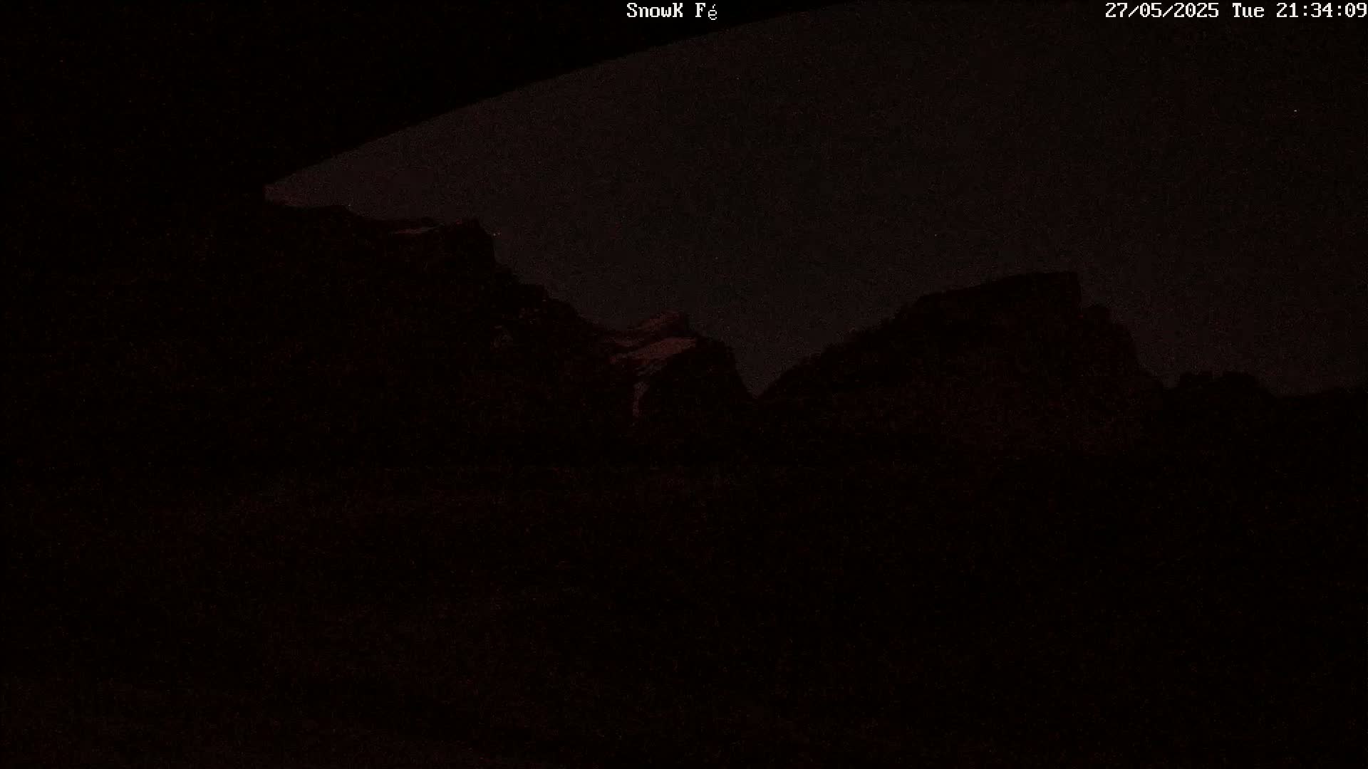 A nighttime view of dark, mountainous terrain under a clear, starlit sky.