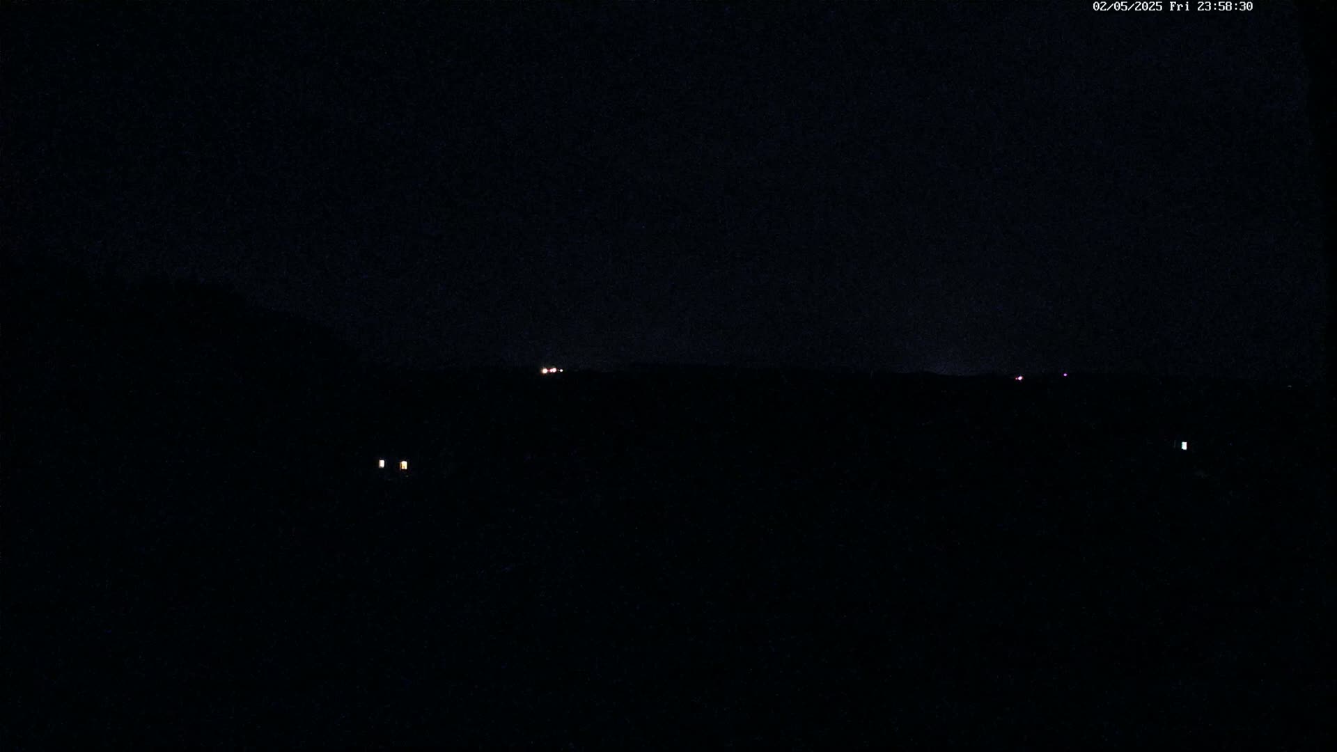 A nighttime view shows a dark landscape with a few faint lights in the distance.
