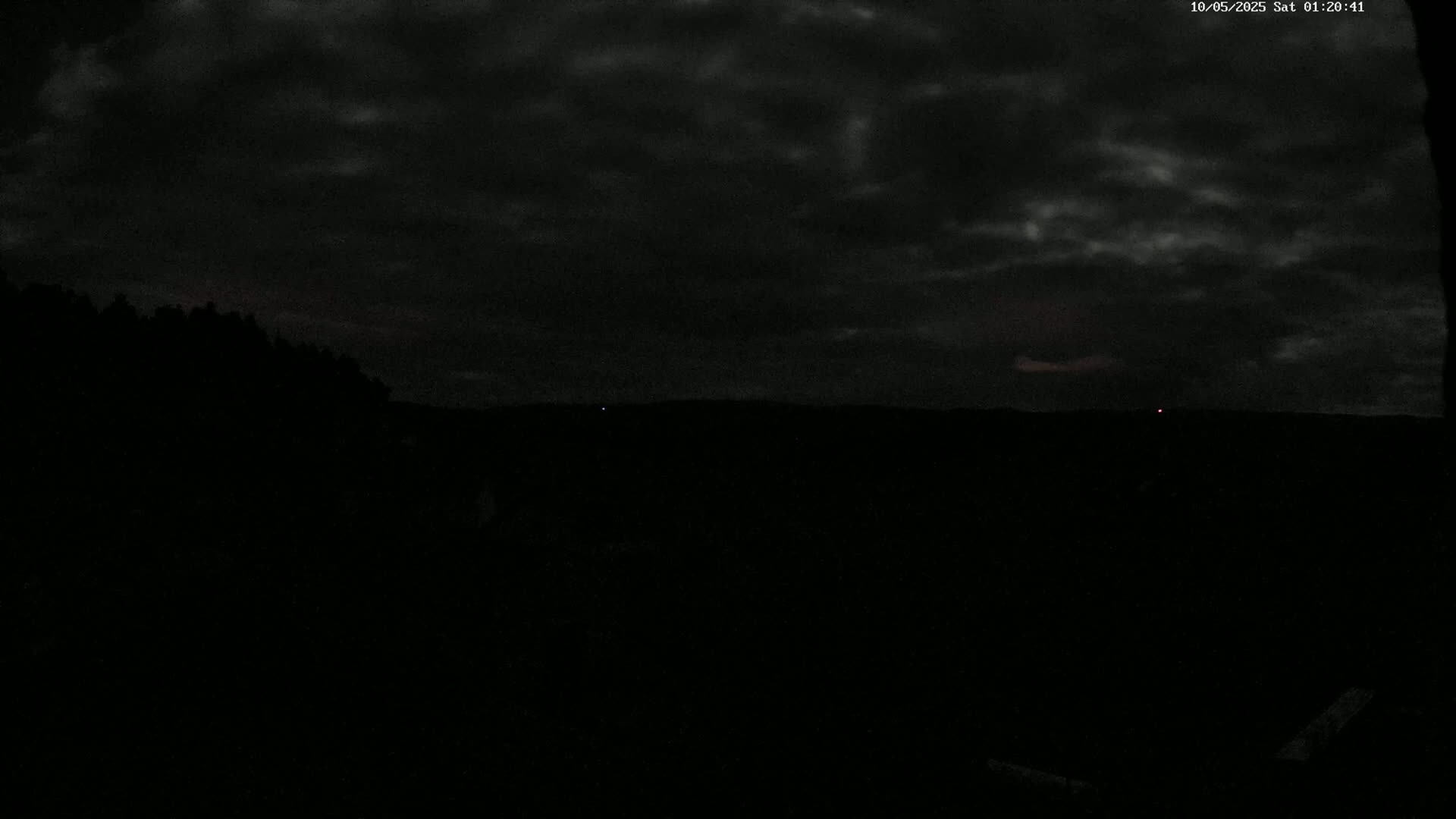 A dark, overcast night sky over a silhouetted landscape.
