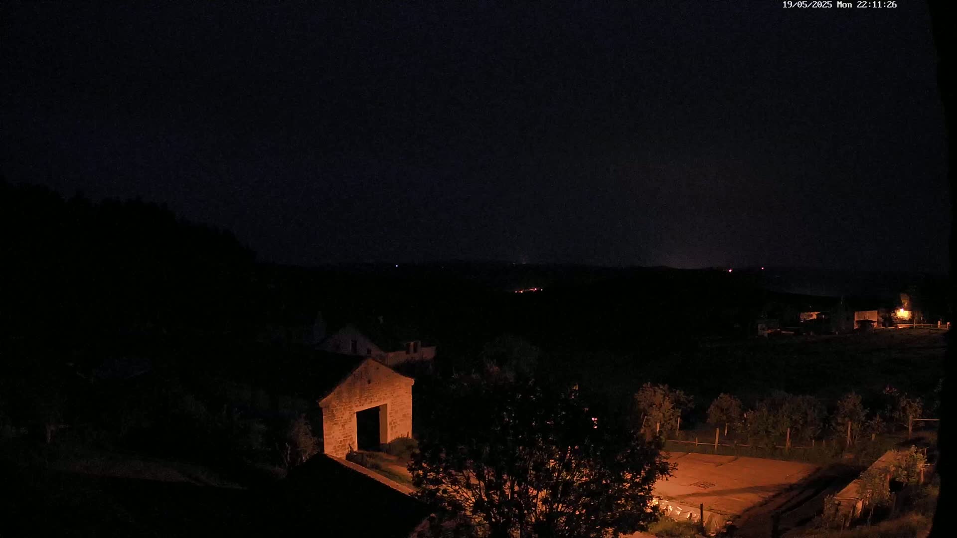 A nighttime view of a stone building and surrounding landscape, under a dark sky.