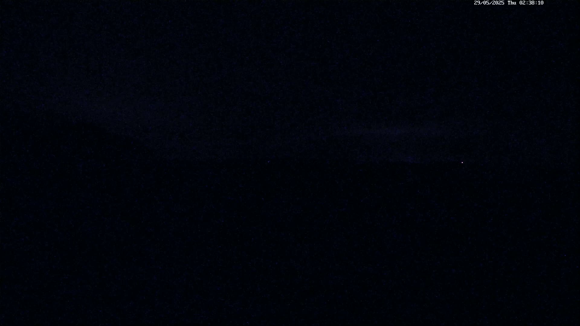 A dark night sky with a few faint stars and a thin band of clouds near the horizon.