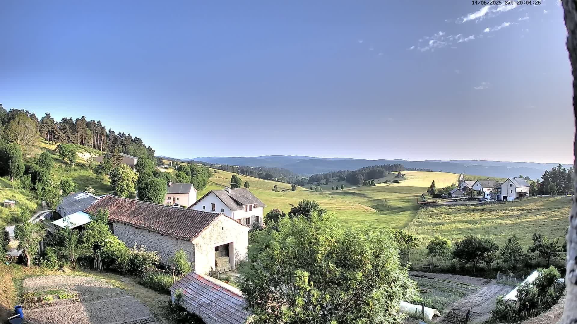 Stone buildings and green fields stretch out into rolling hills under a mostly clear blue sky.