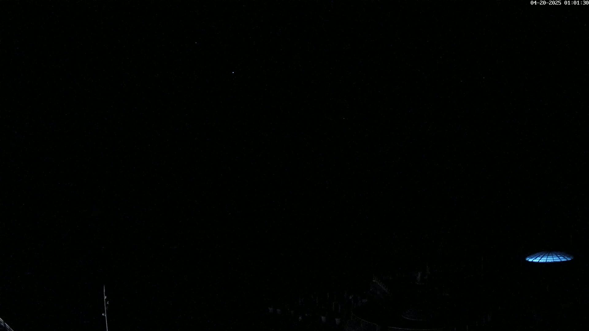 A dark, clear night sky shows a few stars above a dimly lit, low-lying structure with a domed, glowing top.