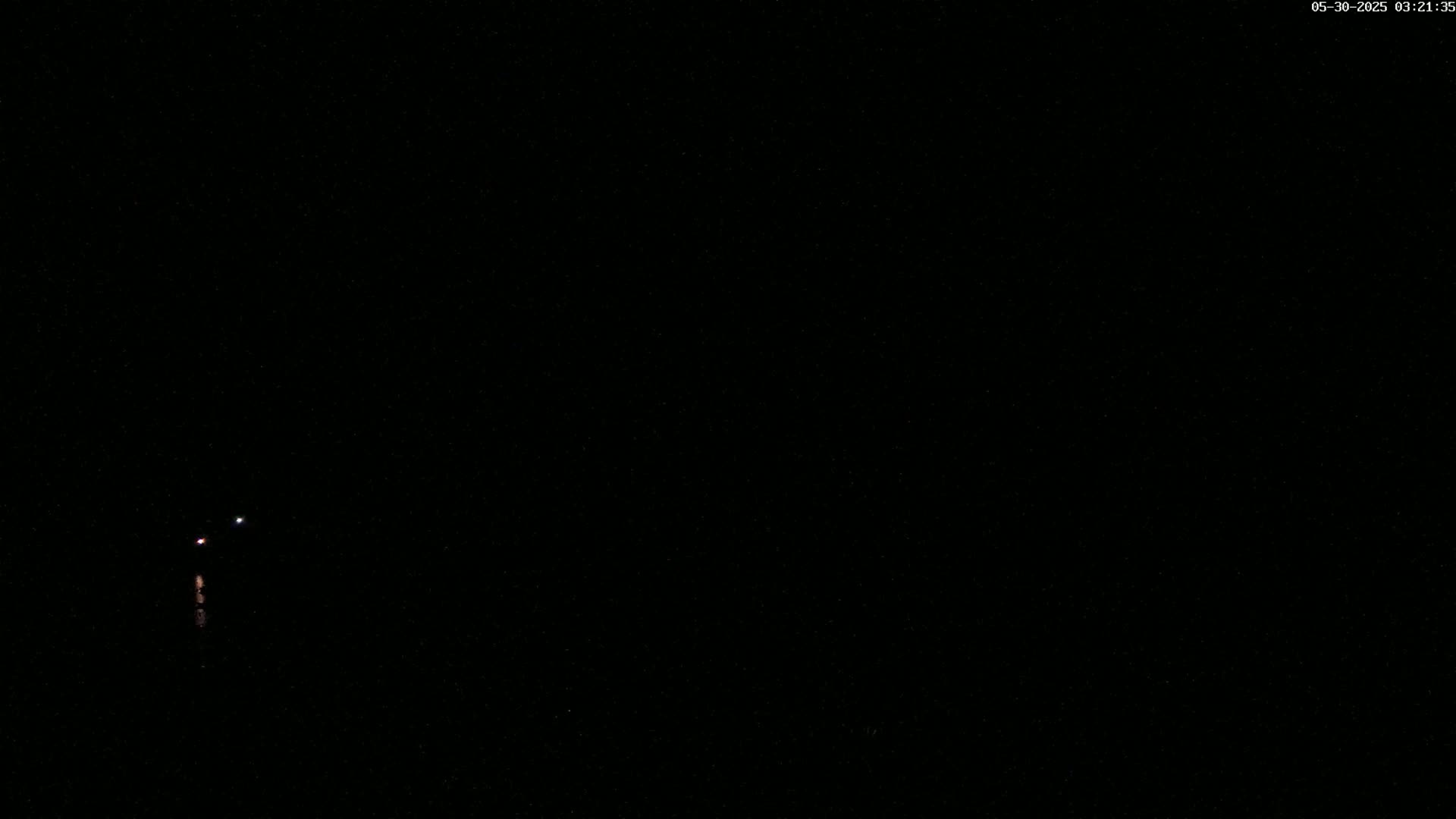 A dark, nighttime scene shows two small, faint lights in the distance.