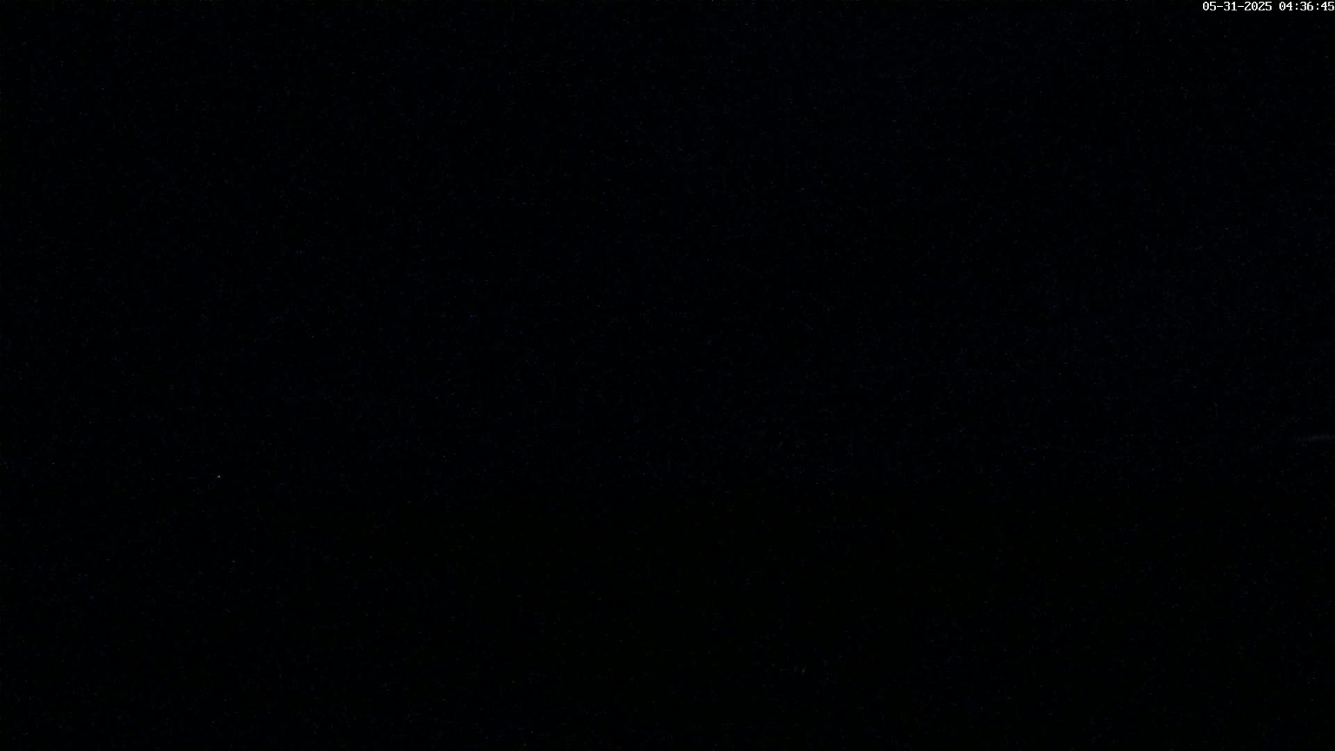 The image is a completely dark, black field, possibly depicting a nighttime scene.