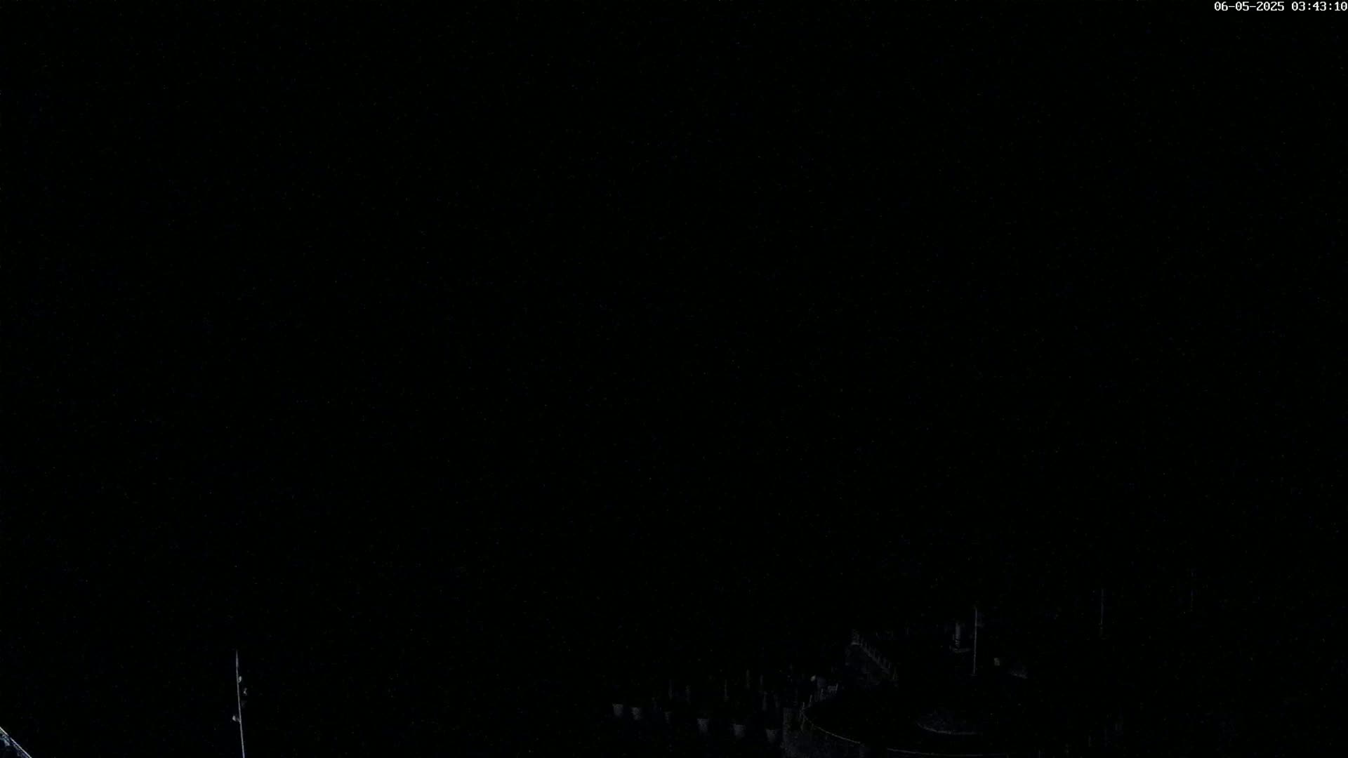 A dark nighttime scene shows a dimly lit structure at the bottom of the frame against a completely black sky.