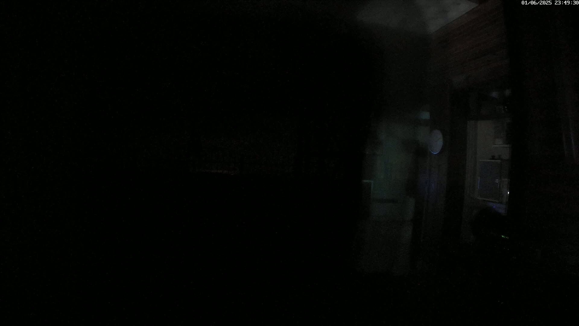 A dark interior room is dimly lit, showing a partially visible doorway and a small portion of another room beyond.