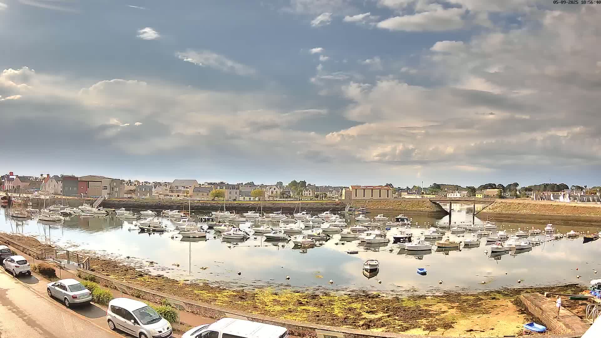 A calm harbor filled with numerous small boats under a partly cloudy sky.
