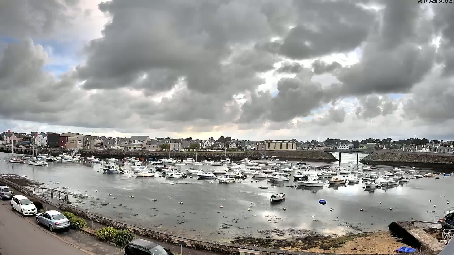 Many boats are moored in a harbor under a cloudy sky.