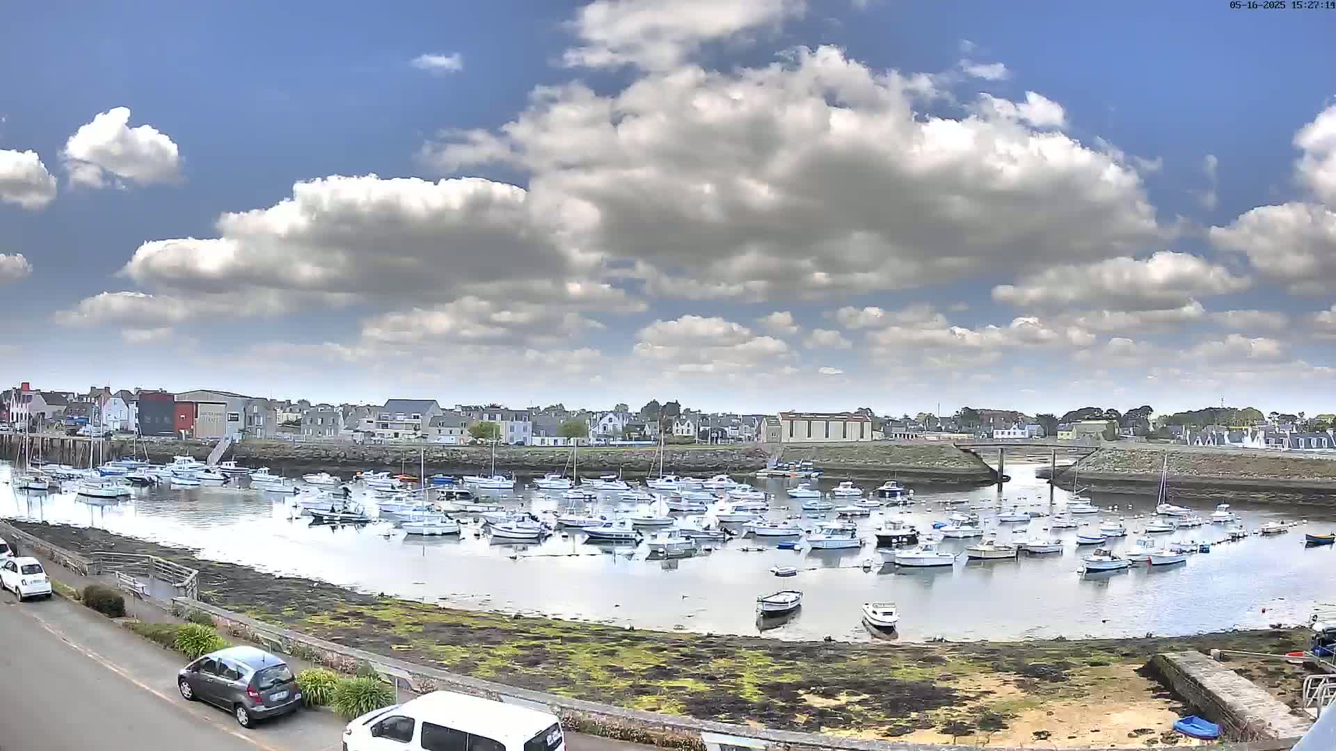 A harbor filled with numerous small boats under a partly cloudy sky.