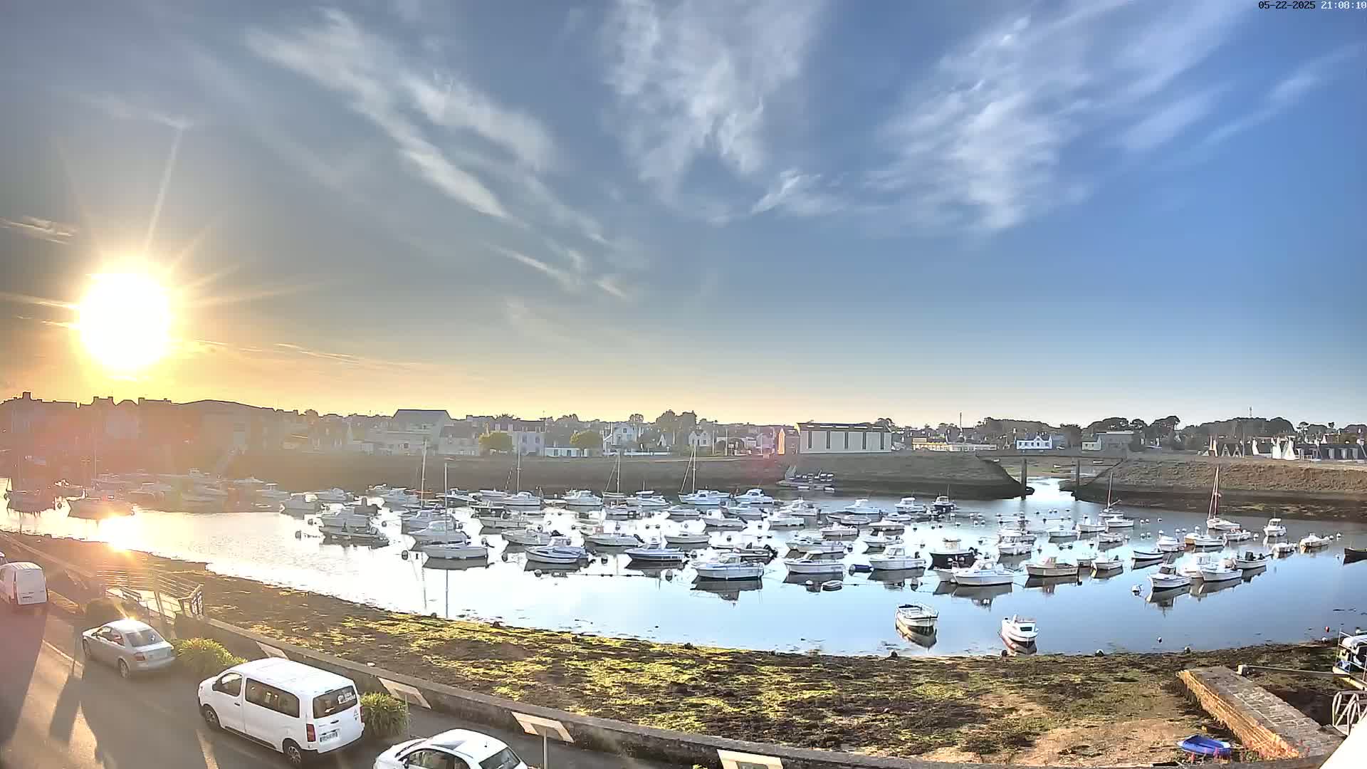 A harbor filled with numerous small boats is seen at sunset under a mostly clear sky.