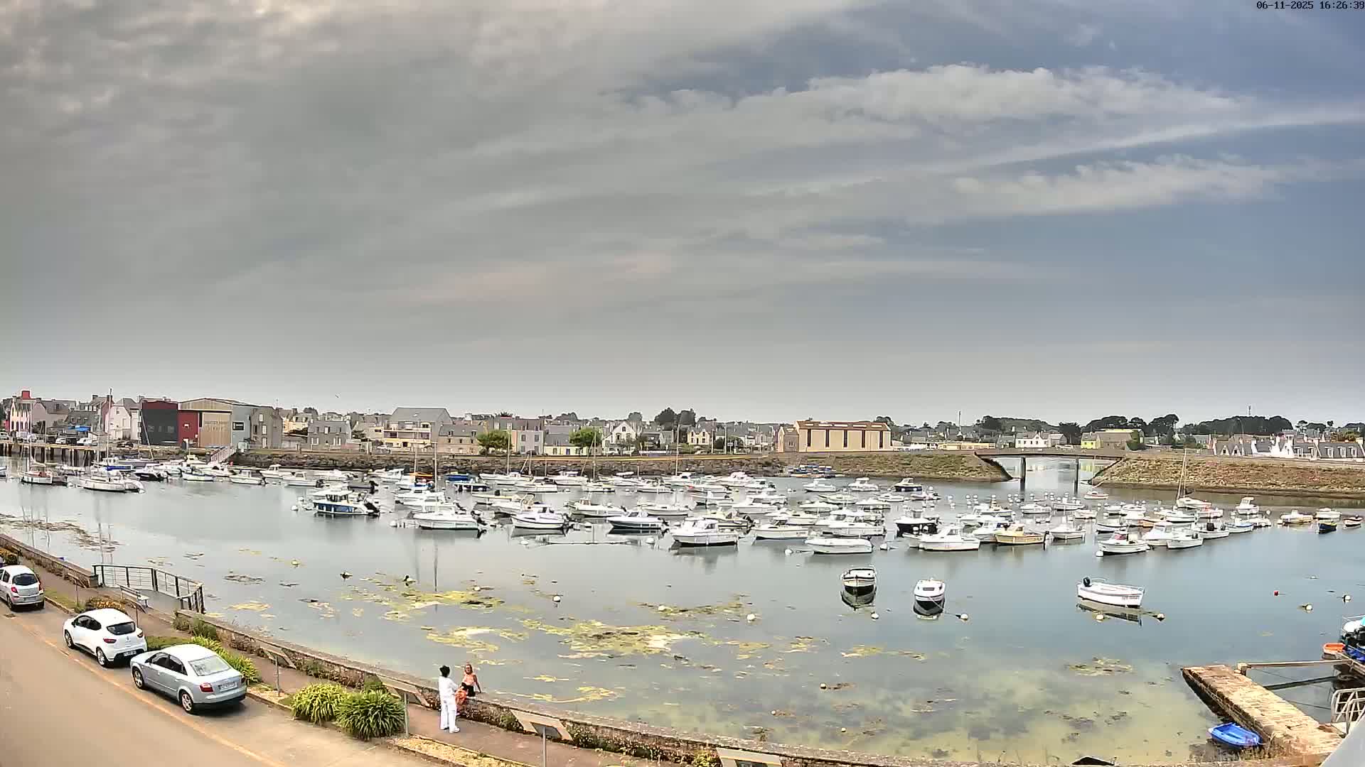 A harbor filled with numerous small boats under a partly cloudy sky.