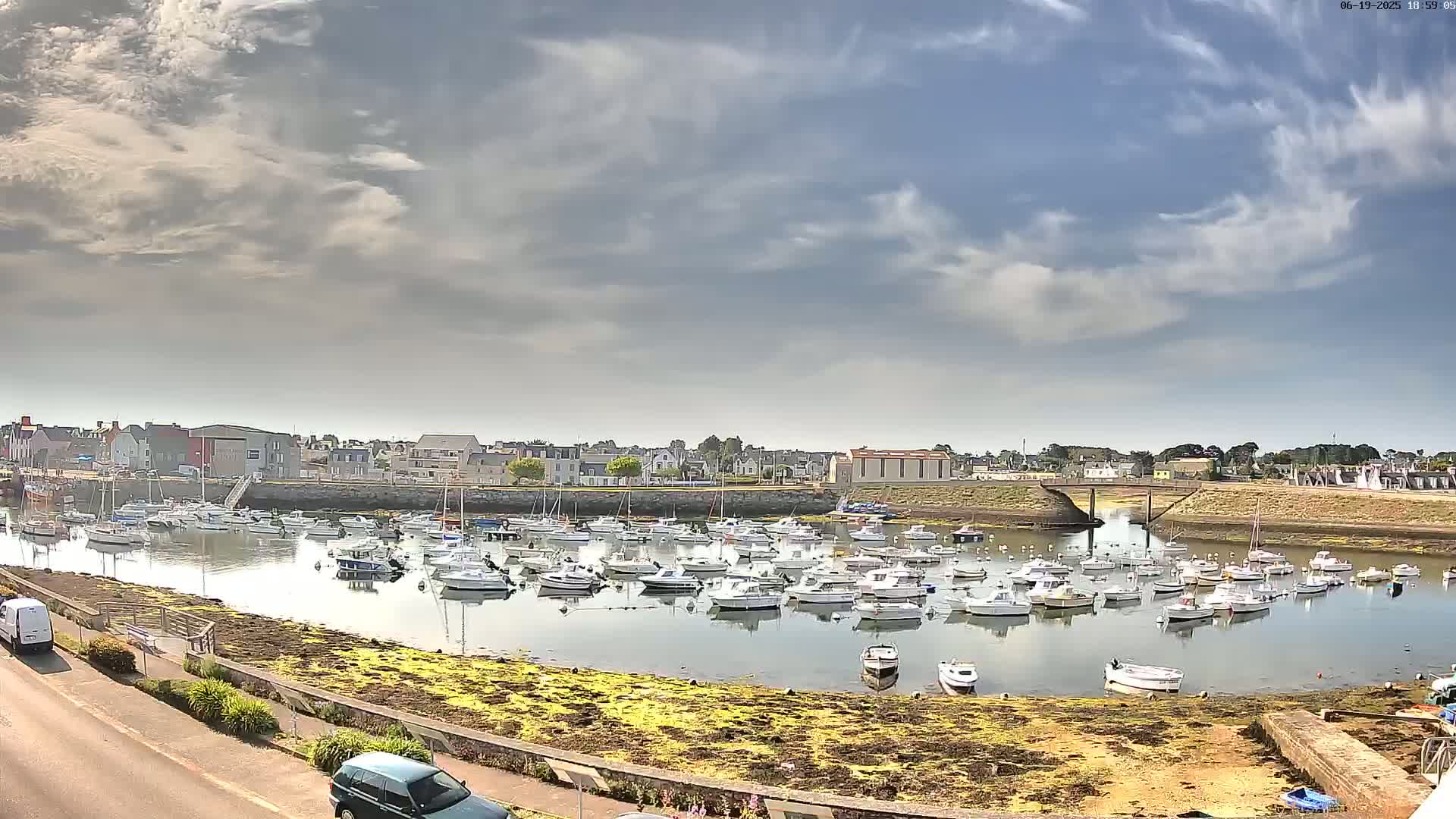 A harbor filled with numerous small boats under a partly cloudy sky.