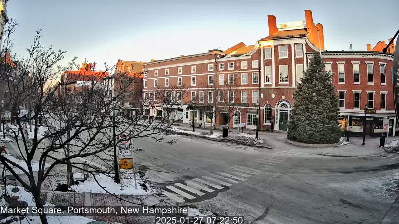 A snow-dusted Market Square in Portsmouth, New Hampshire, shows several brick buildings under a clear, bright sky at sunrise.