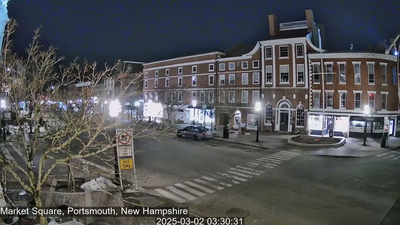 A nighttime street scene shows a mostly empty Market Square with a few cars and several brick buildings under a clear, dark sky.