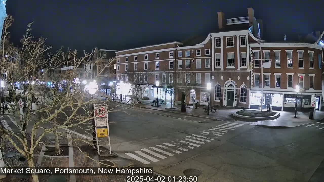 A mostly empty, nighttime market square is shown, with brick buildings lining the street under a clear, dark sky.