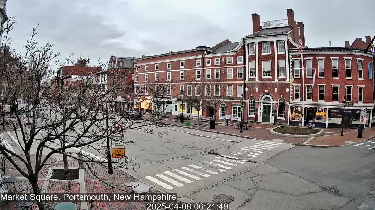 A mostly empty town square with several brick buildings under an overcast sky.