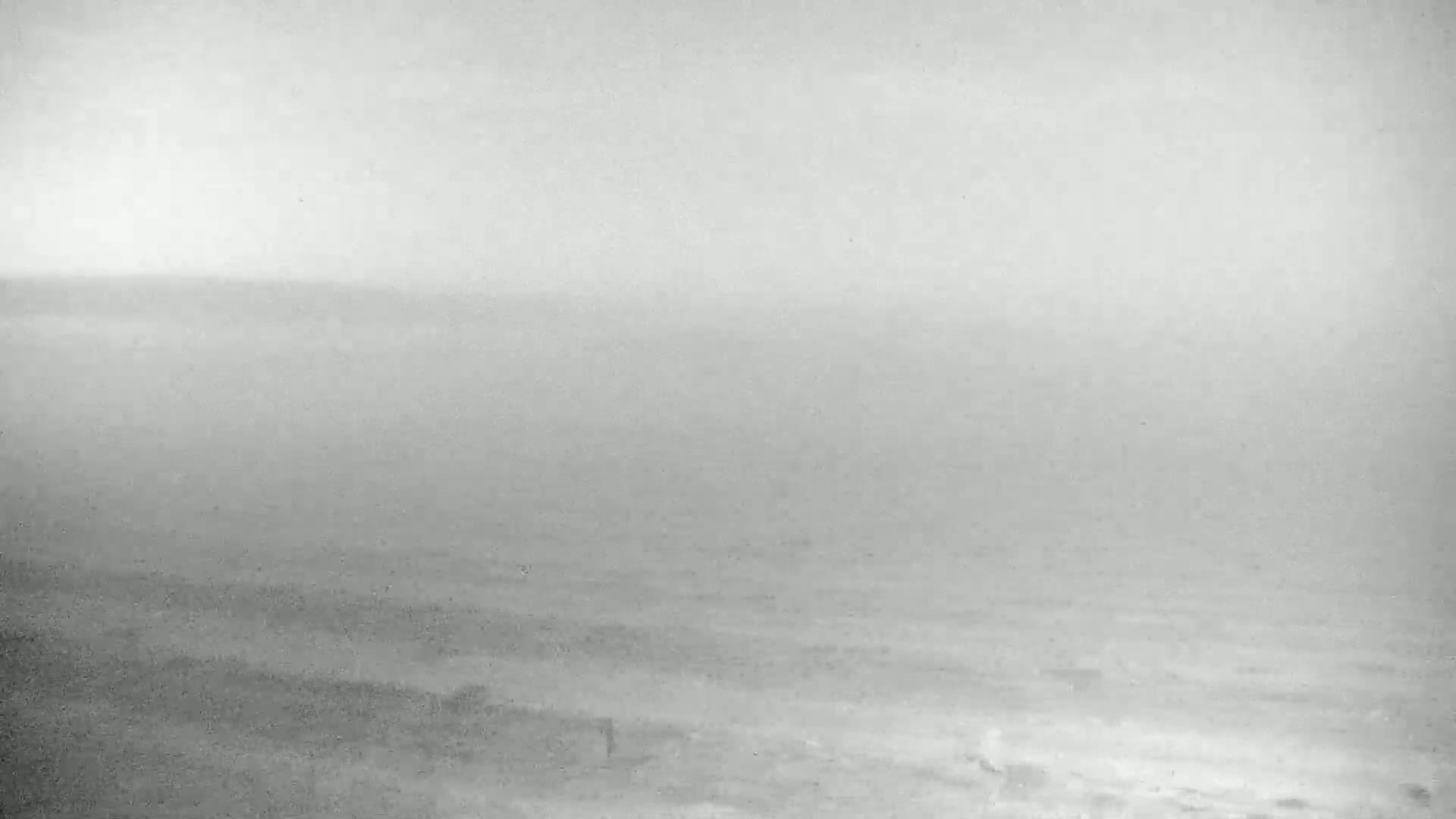A hazy, overcast day shows a beach and ocean in the distance.