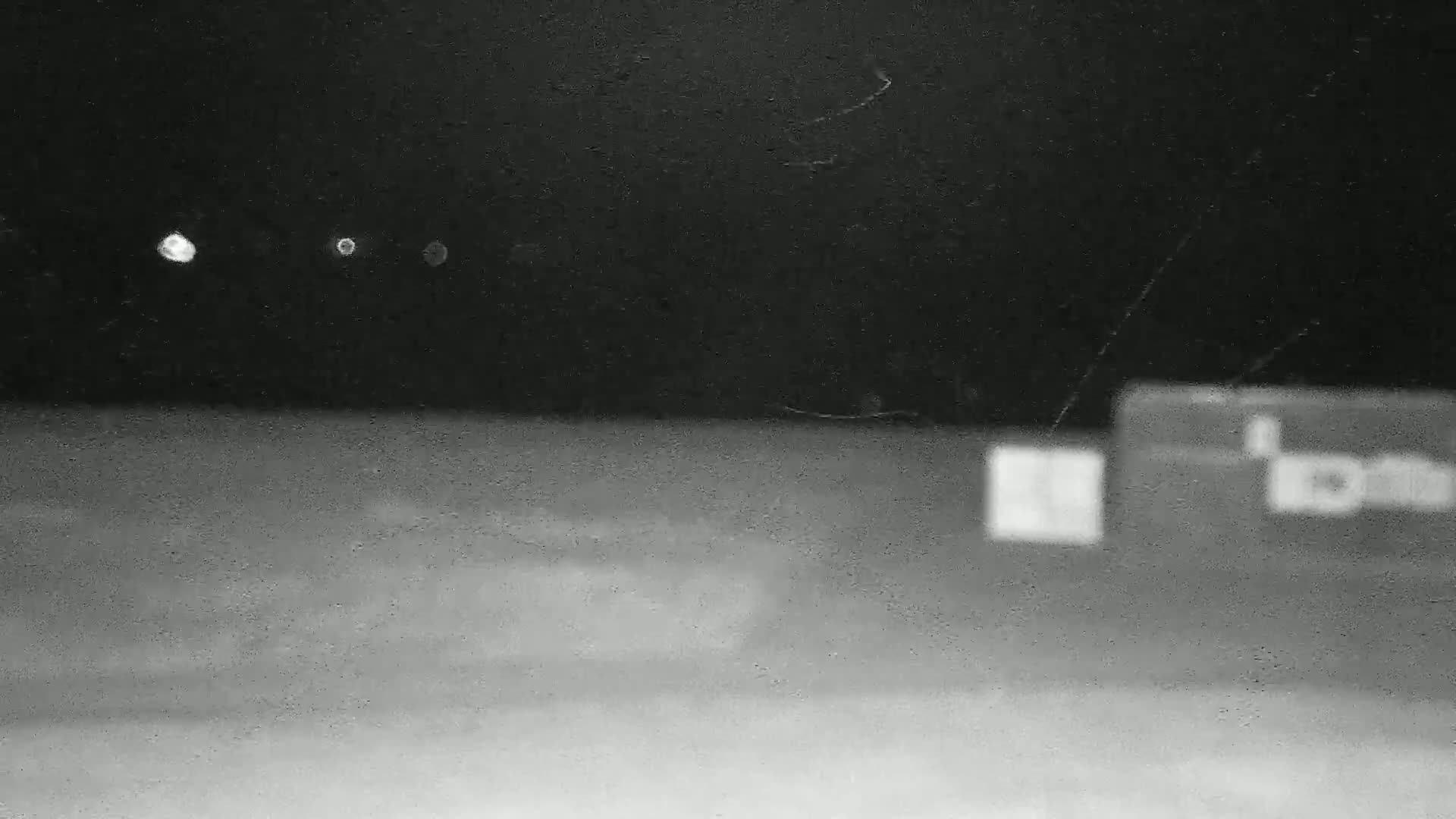 Three blurry lights are visible in the dark night sky above a blurred, out-of-focus ground-level scene containing two indistinct, rectangular objects.