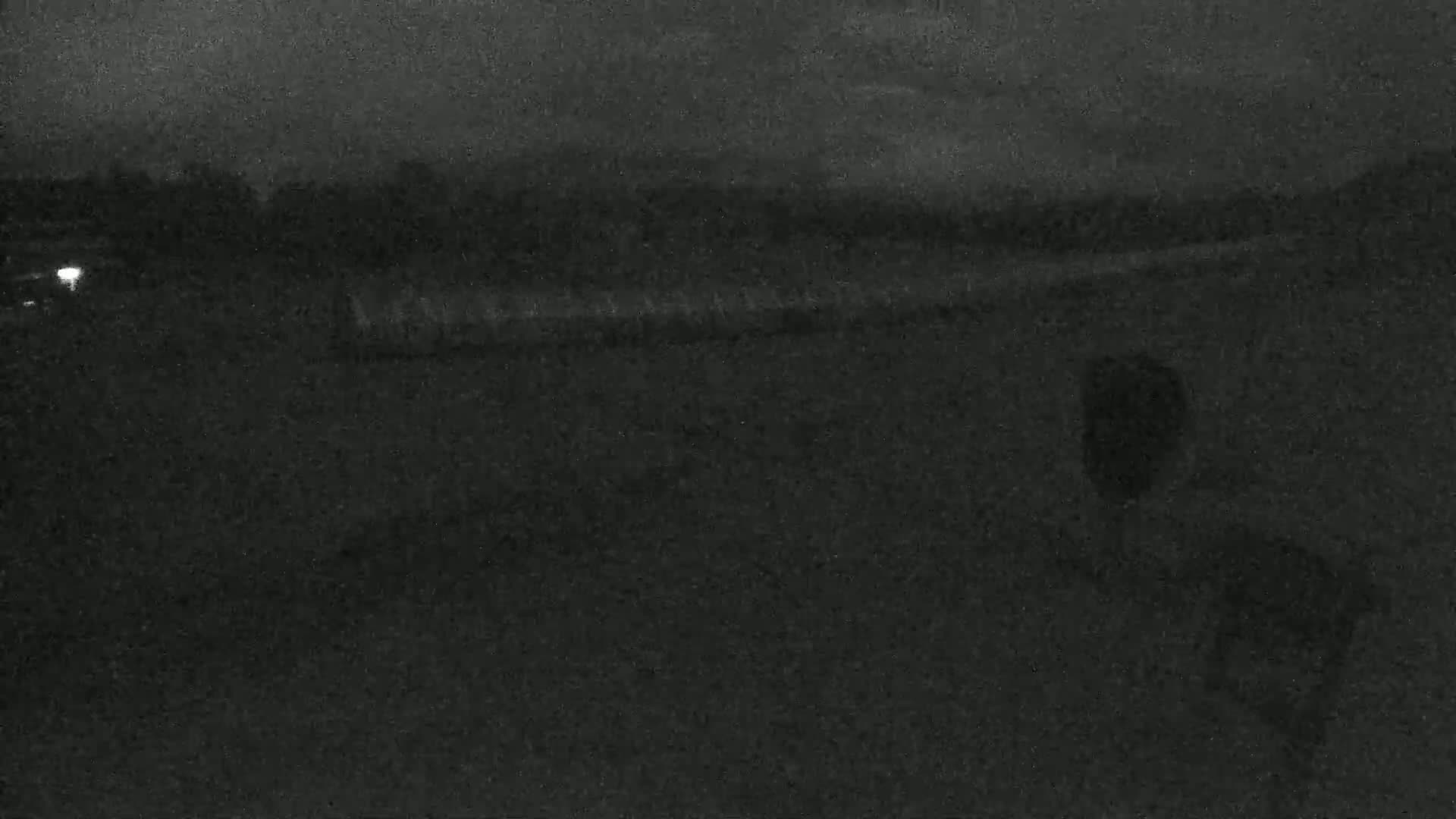 A dark, blurry image shows a mostly featureless landscape at night under an overcast sky.