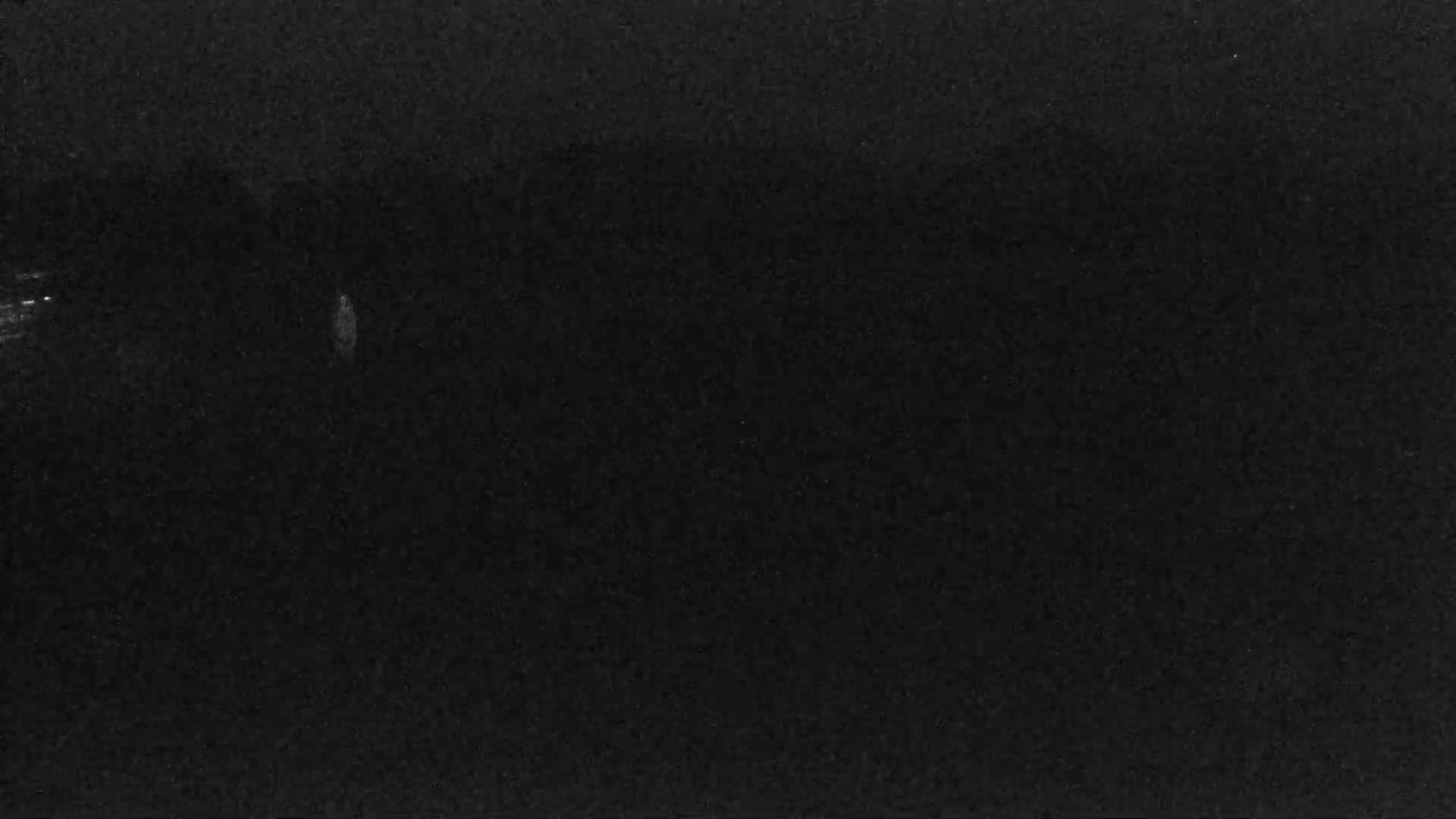 A dark, possibly nighttime, image shows a mostly black background with faint, indistinct light sources.