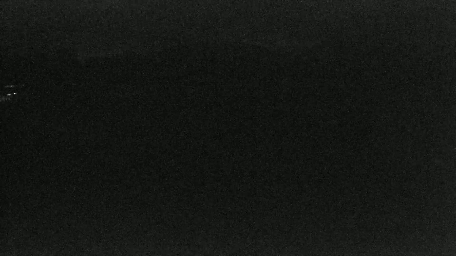 A mostly black image with a few faint, speckled lights possibly indicating nighttime.