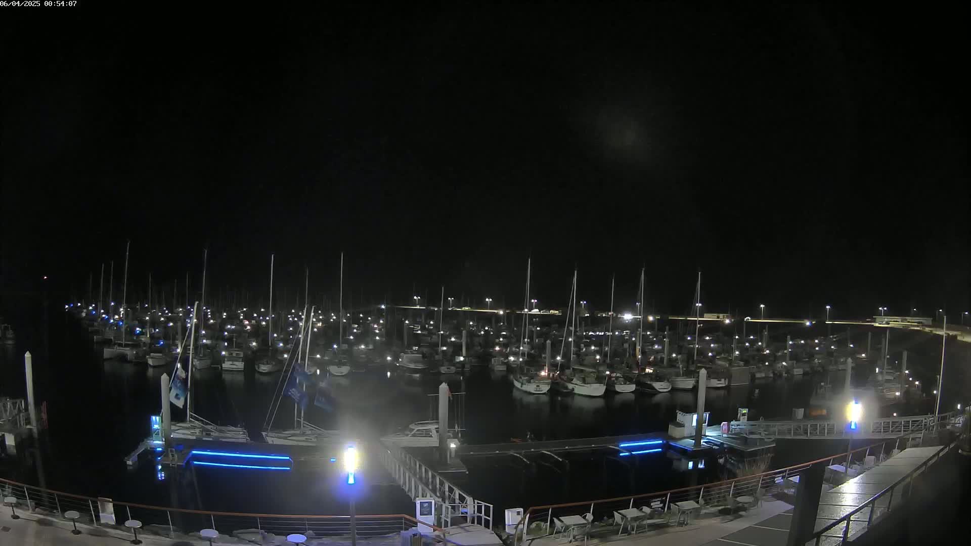 A nighttime view of a marina filled with numerous boats docked under a dark sky.
