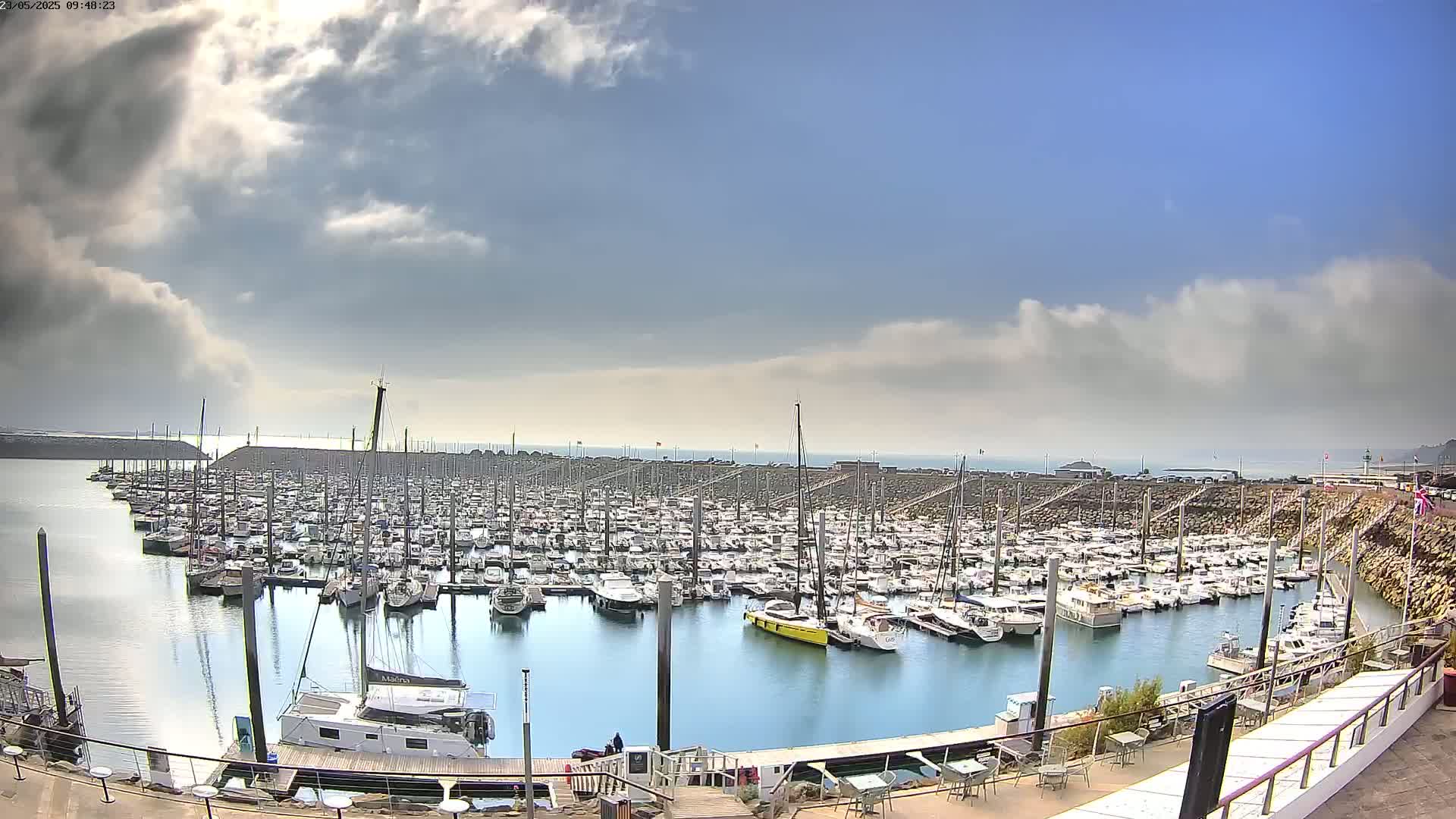 A large marina filled with numerous boats is seen under a partly cloudy sky.