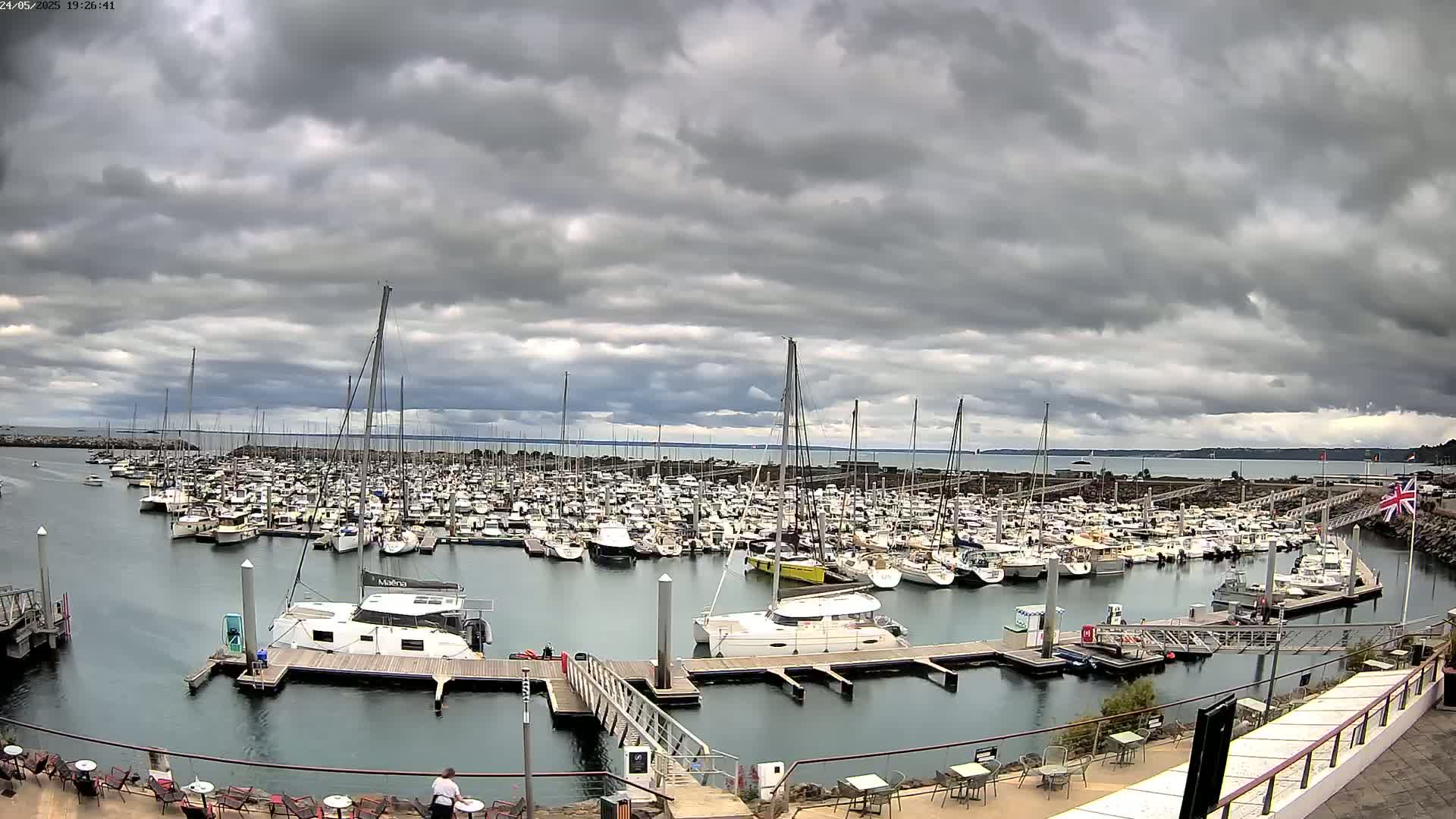 A large marina filled with many boats is seen under a heavily clouded sky.