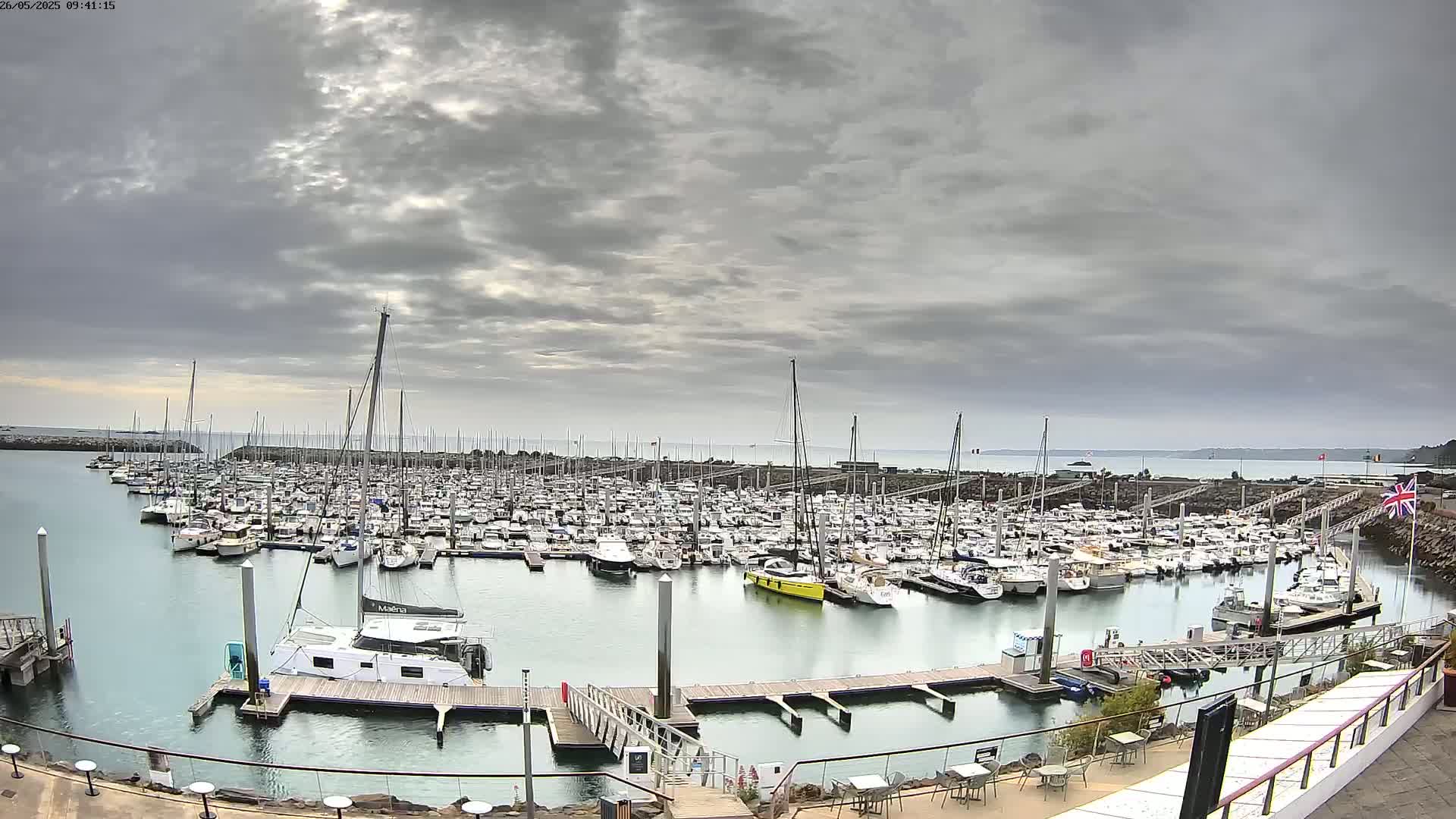 A large marina filled with numerous sailboats and motorboats is shown under an overcast sky.