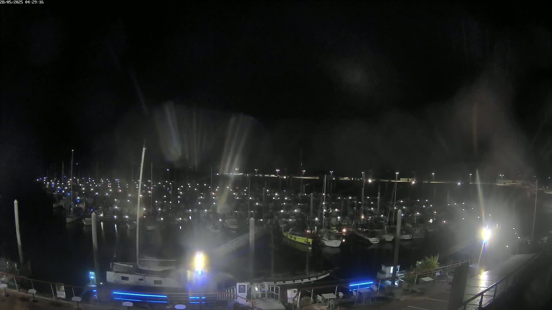 A nighttime, hazy view of a marina filled with many boats illuminated by their lights.