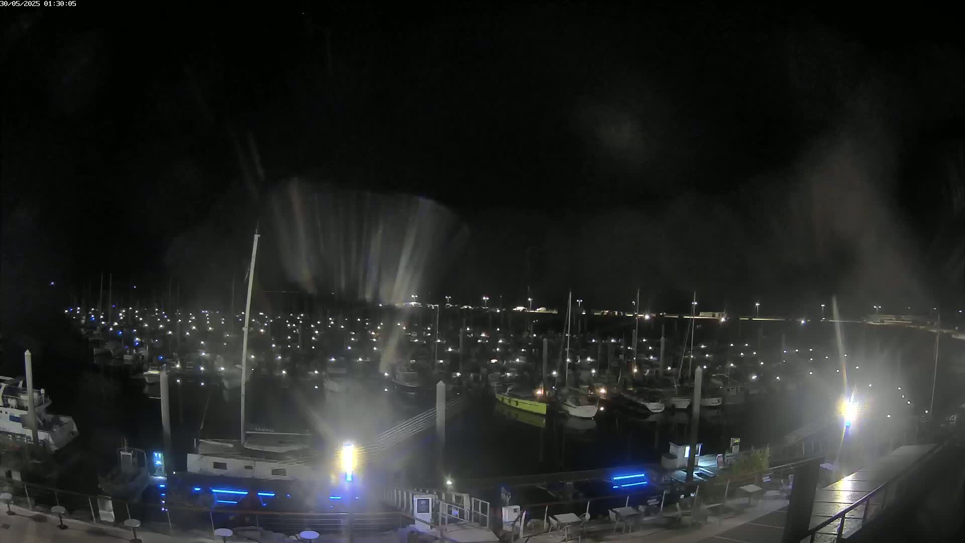 A nighttime, hazy view of a marina filled with numerous boats illuminated by individual lights.