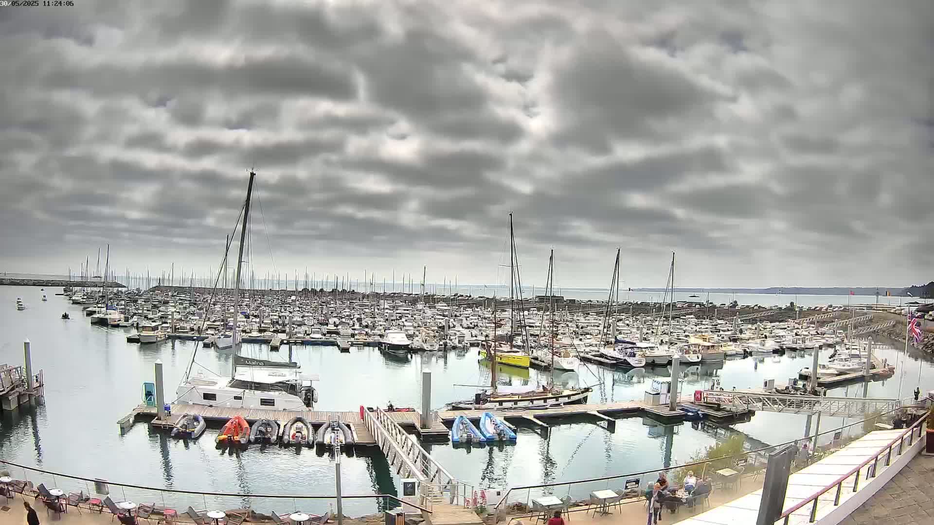A large marina filled with numerous boats is shown under a cloudy sky.