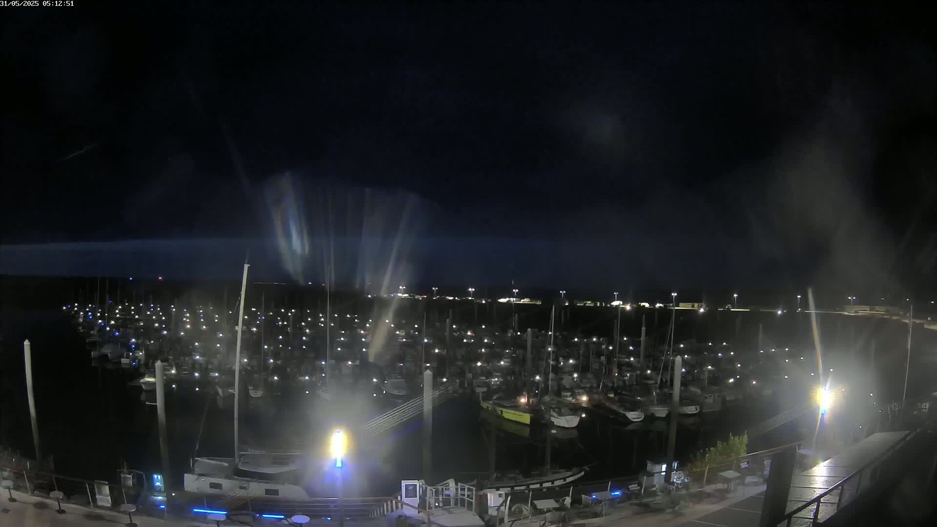 A nighttime view of a marina filled with many boats under a dark, possibly cloudy sky.