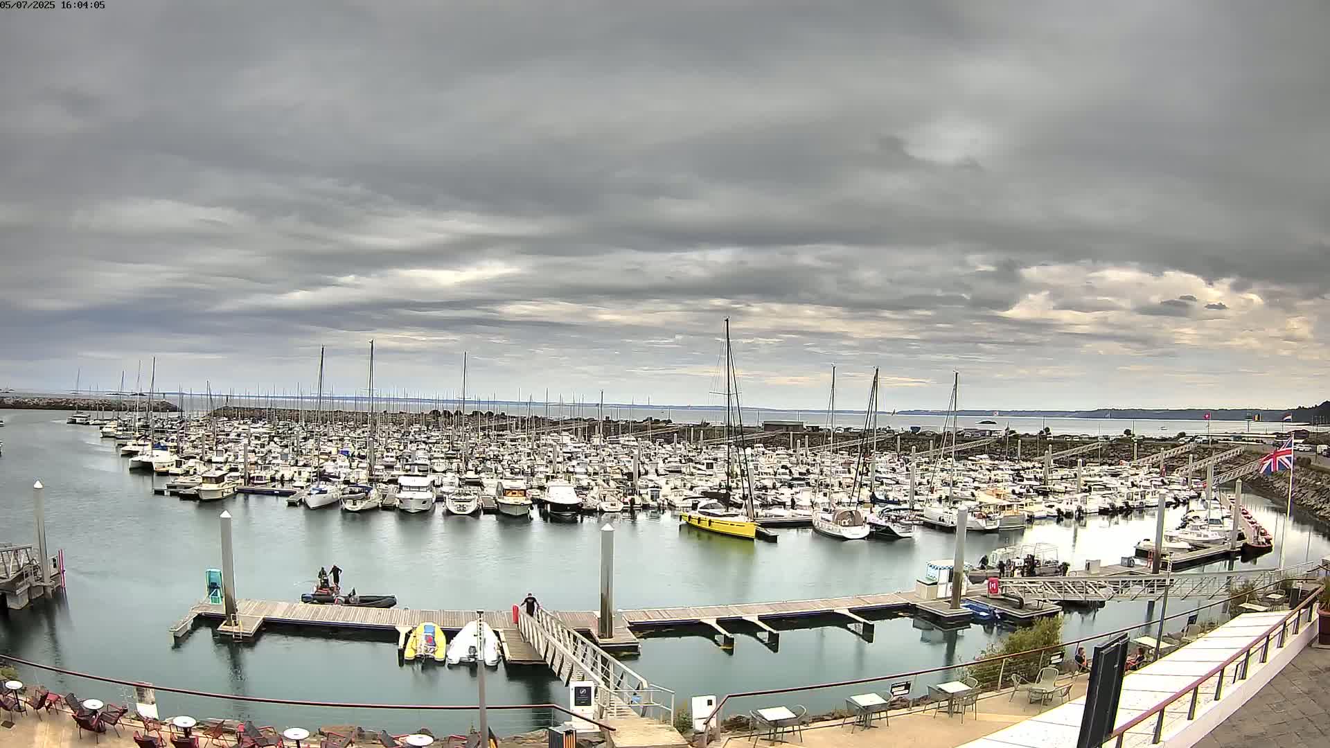 A large marina filled with numerous boats is situated under an overcast sky.