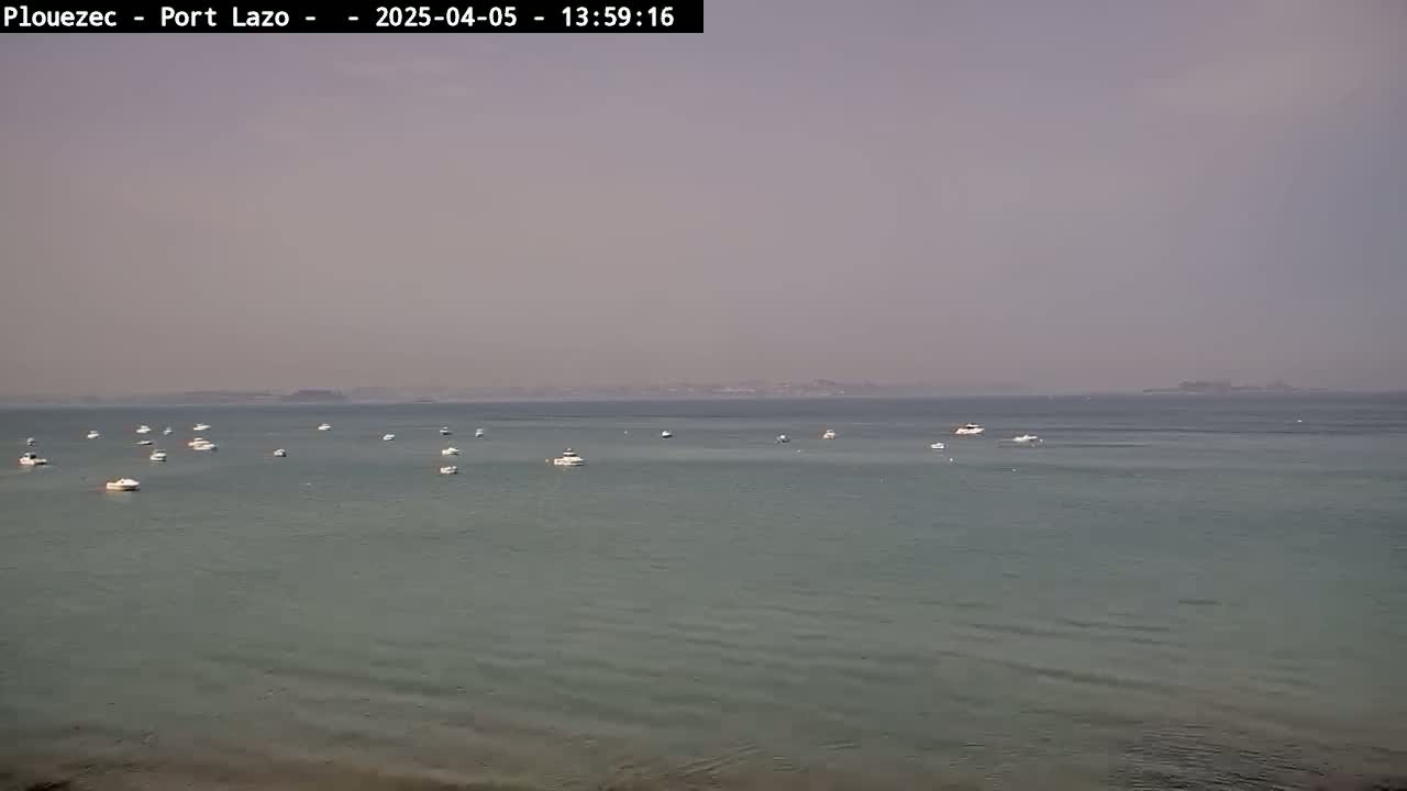 Several small boats are scattered across a calm, hazy sea with a distant landmass visible on the horizon.
