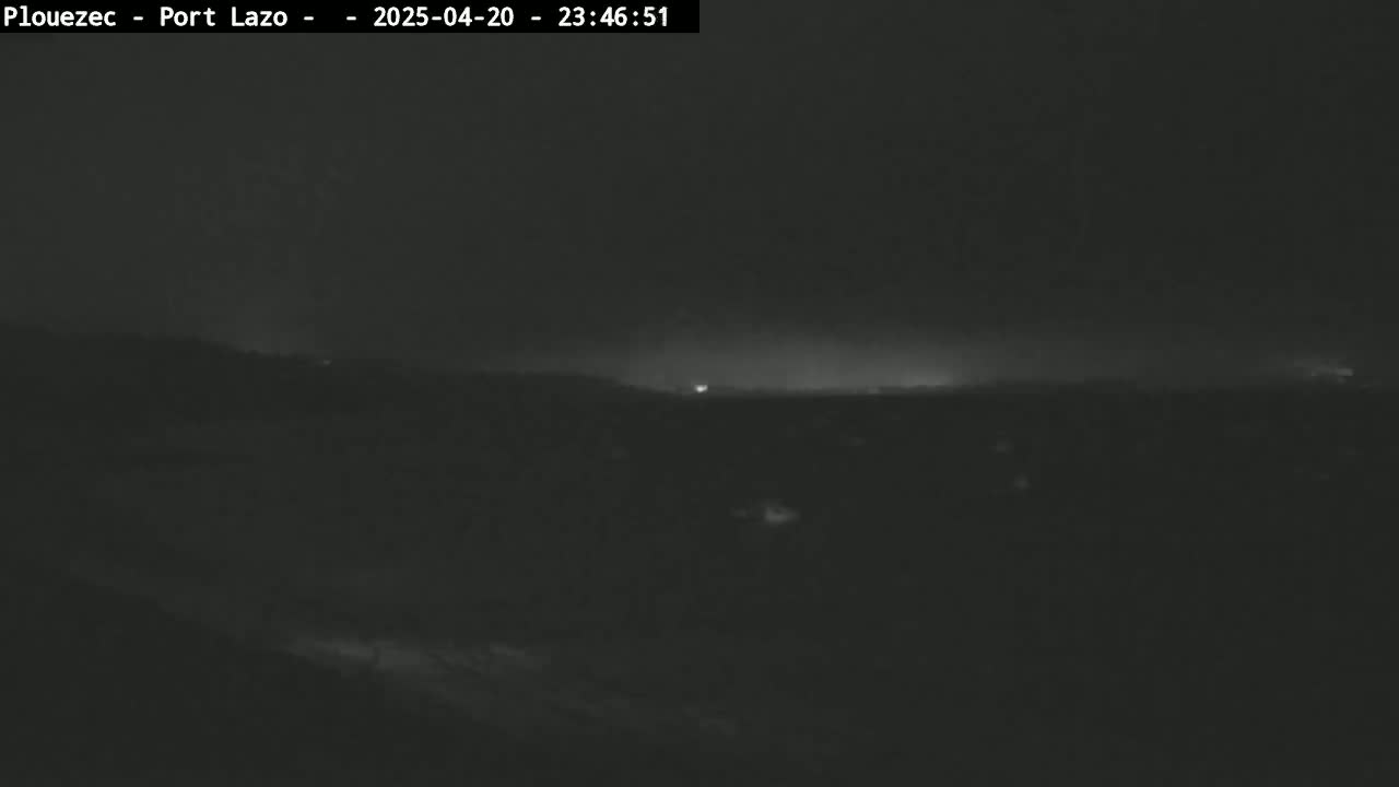 A dark, nighttime scene shows a flat, dark landscape under a mostly clear sky.