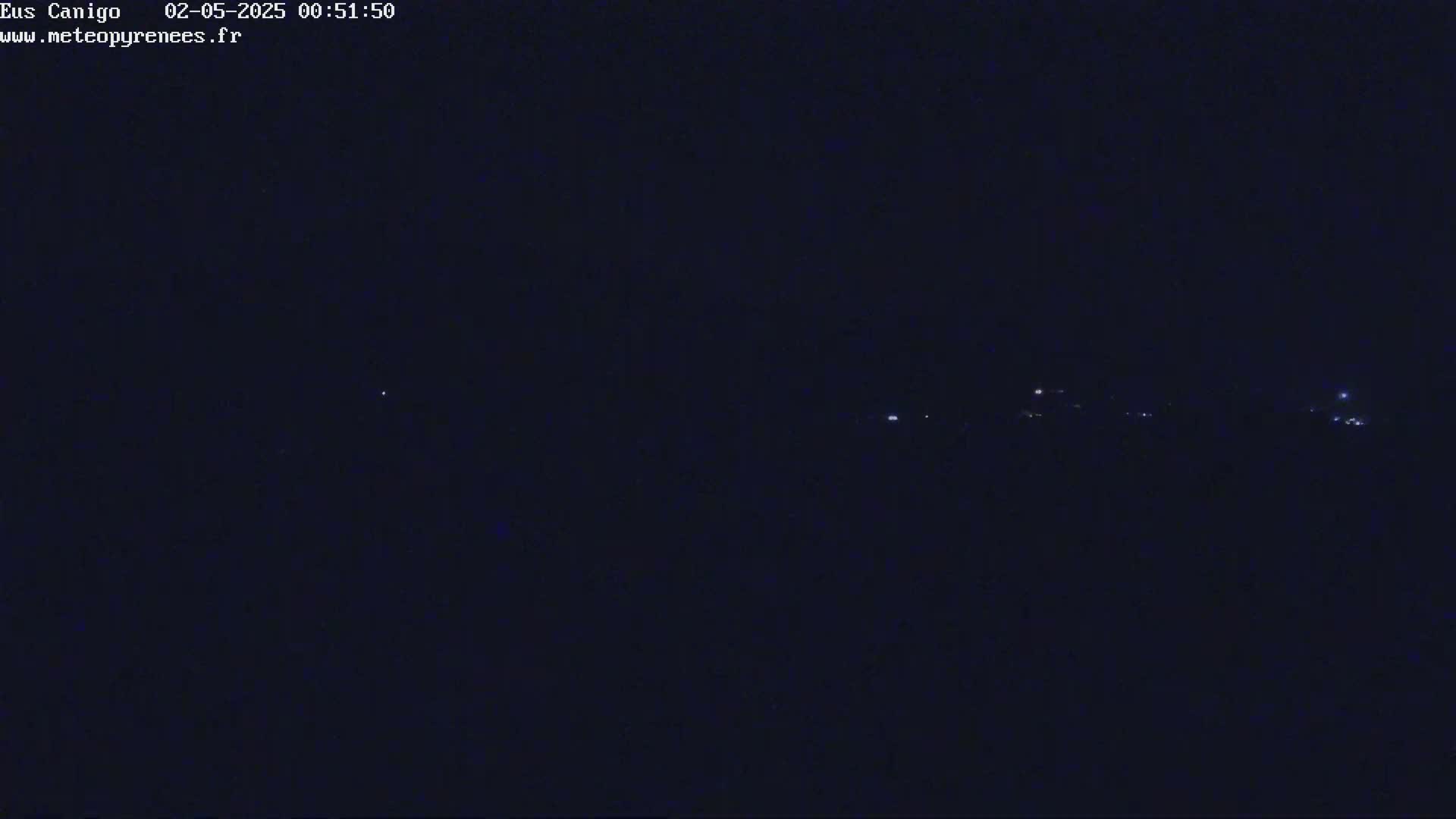 A dark nighttime scene shows a few faint lights in the distance.