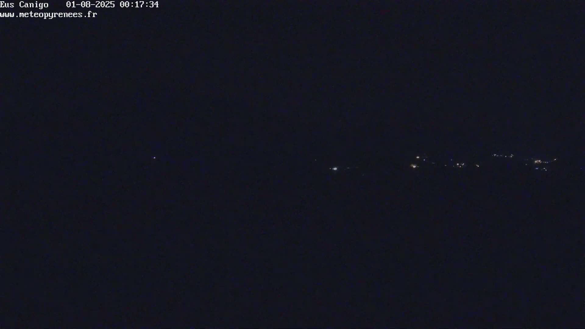 A nighttime long shot shows a dark landscape with a few faint lights in the distance.